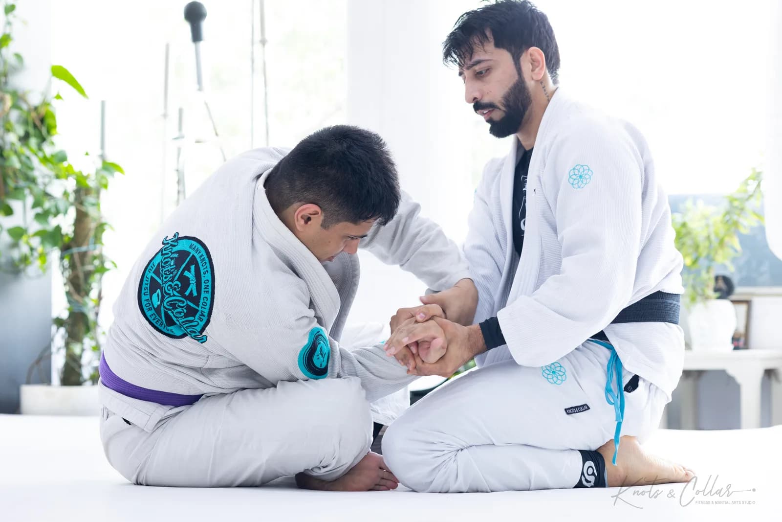 A Brazilian Jiu-Jitsu coach guiding a student's grip one-on-one during a private lesson at Knots & Collar in Defence Colony, New Delhi