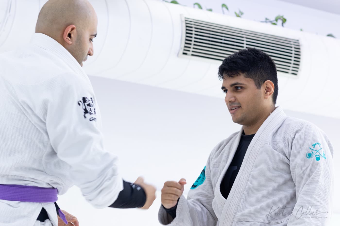 A coach talking a student through a technique in gi jiu-jitsu at Knots & Collar, Defence Colony