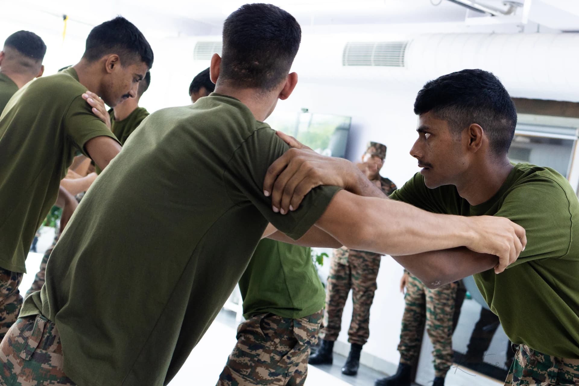 Two soldiers squaring off in a standing grappling drill while others watch, at Knots & Collar, New Delhi